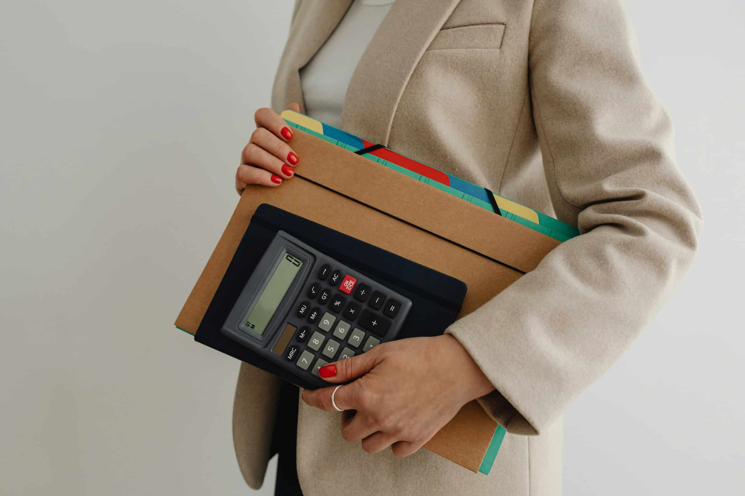 Mulher segurando uma calculadora e pastas organizadas, representando a importância da organização no trabalho e o uso de ferramentas adequadas para produtividade.