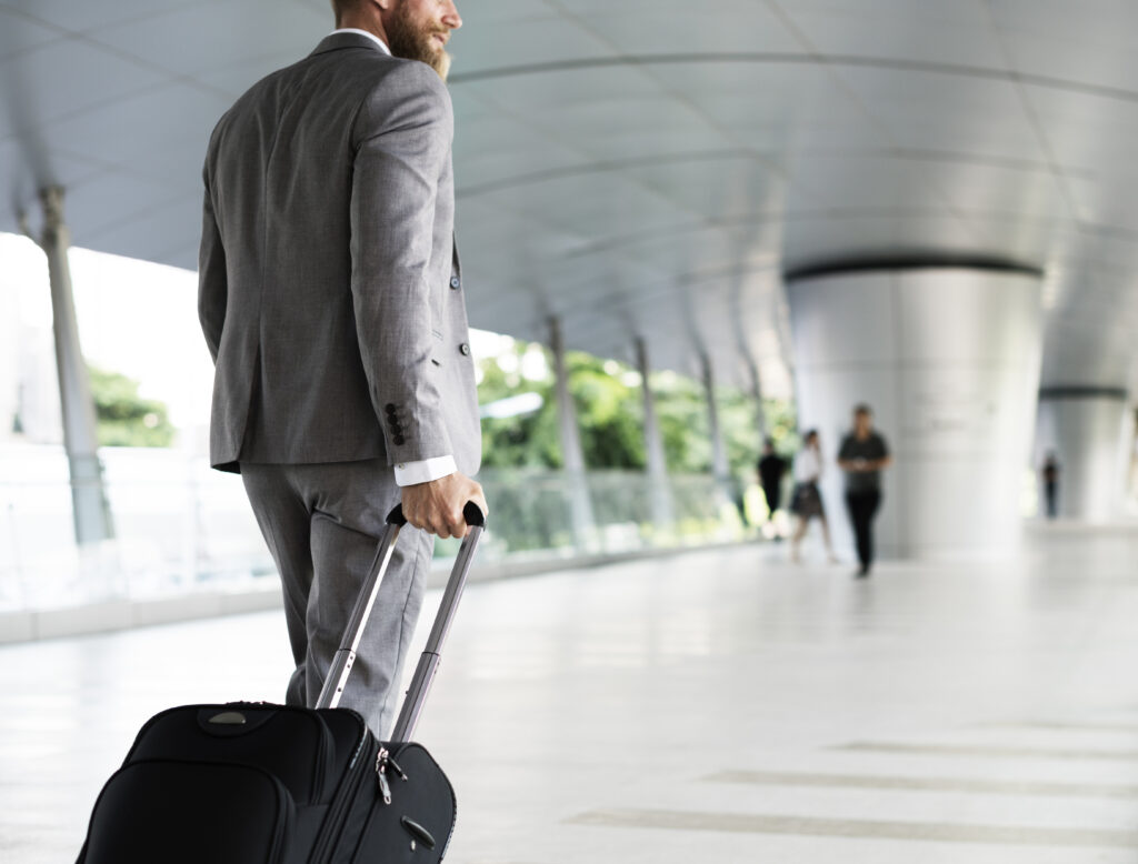 Imagem de um homem vestido de terno com uma mala em um aeroporto