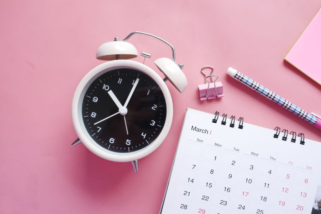Relógio em cima da mesa com um calendário - Foto: Freepik