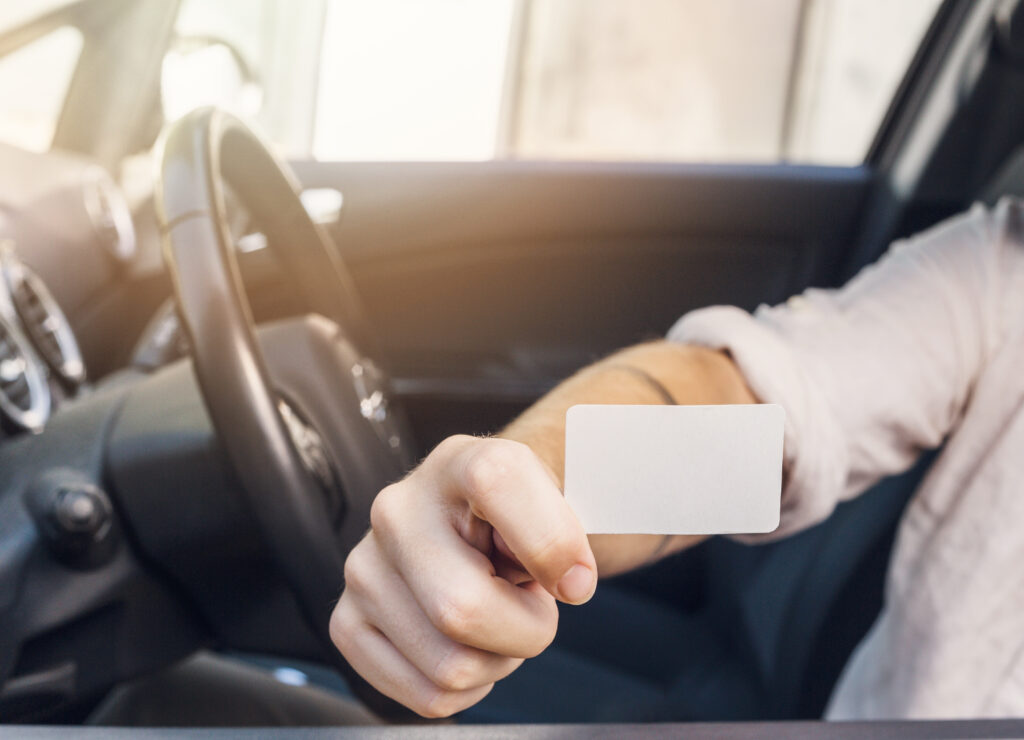 Pessoa dentro de um carro segurando um cartão