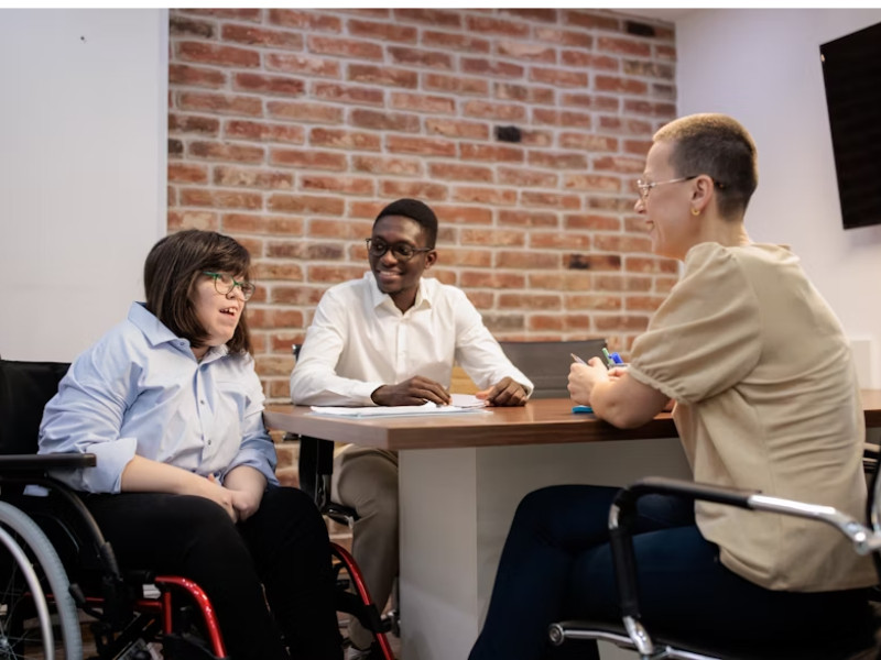 A imagem representa um ambiente corporativo inclusivo, onde pessoas com deficiência (PCD) participam ativamente das atividades profissionais. Ela simboliza diversidade, acessibilidade e igualdade de oportunidades no mercado de trabalho, reforçando a importância da inclusão real e do respeito às capacidades individuais no ambiente empresarial.