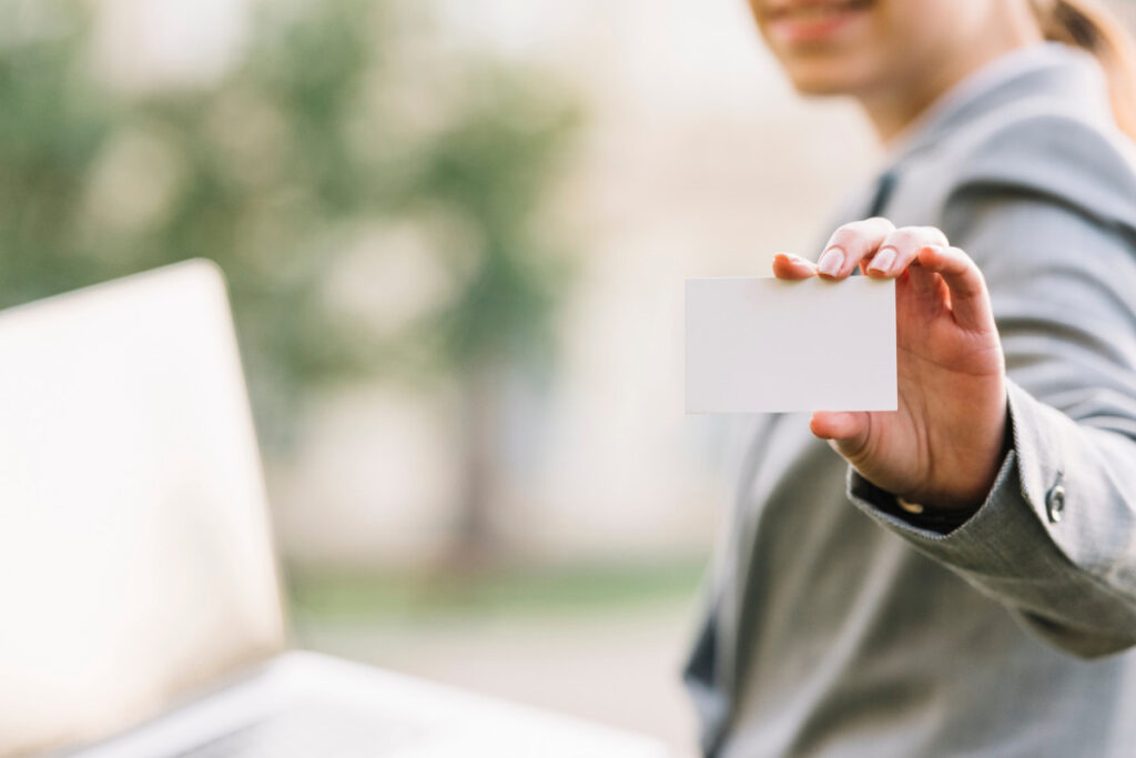 Descrição da Imagem com Foco em Cartão de Benefício Empresarial
A imagem é um close-up com foco na mão de uma pessoa, que está segurando um cartão branco em branco, frequentemente usado para representar um cartão de visita, identificação ou um cartão de benefícios empresariais/corporativo.