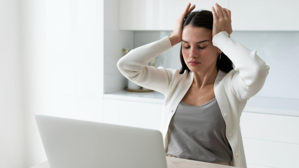 Esta imagem retrata uma cena comum de estresse, cansaço ou sobrecarga mental no ambiente de trabalho.