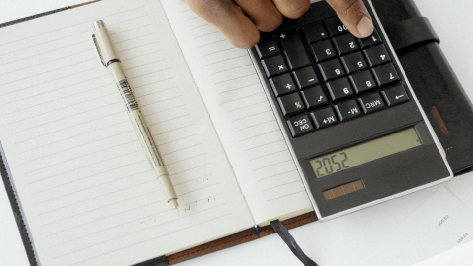 Esta imagem apresenta uma visão aérea em estilo flat lay de uma mesa de trabalho, focando em atividades de planejamento ou contabilidade.