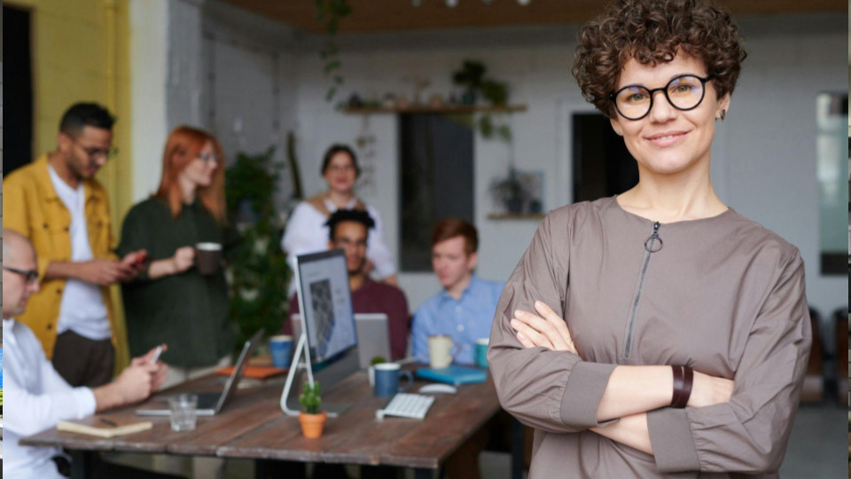 Esta imagem apresenta um contraste interessante entre a liderança individual e o trabalho colaborativo em um ambiente de escritório moderno e informal.