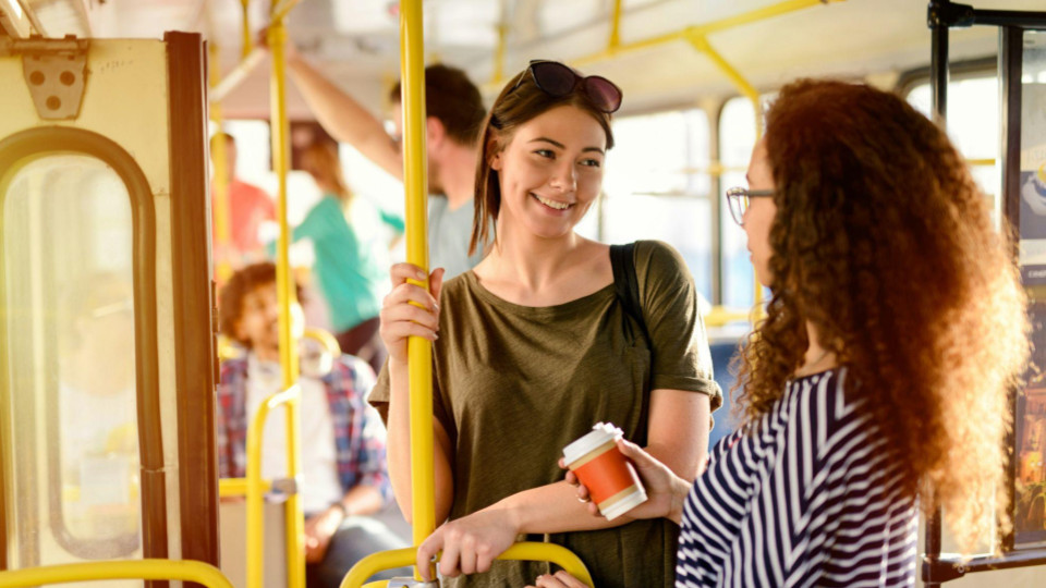 A imagem retrata uma cena casual e descontraída no interior de um transporte coletivo