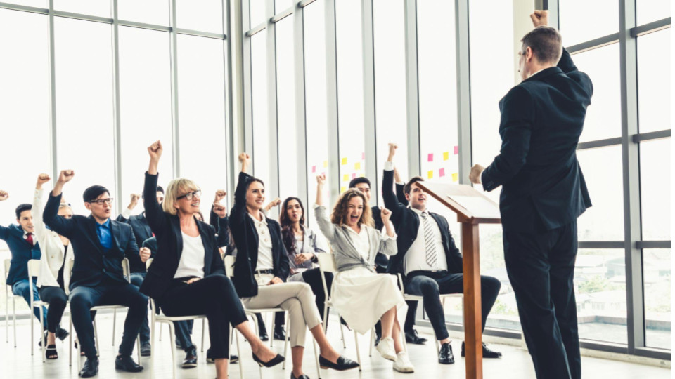 Líder apresenta treinamento para colaboradores em uma conferência corporativa, com equipe reunida