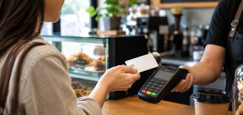 Colaborador usando o cartão Eva em uma situação cotidiana, como fazendo uma compra em um estabelecimento ou pagando pelo celular.
