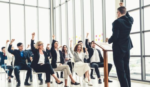 Líder apresenta treinamento para colaboradores em uma conferência corporativa, com equipe reunida