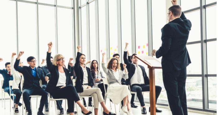 Líder apresenta treinamento para colaboradores em uma conferência corporativa, com equipe reunida