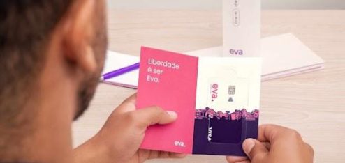 A imagem mostra, em primeiro plano, uma pessoa segurando um cartão de visita da Eva.