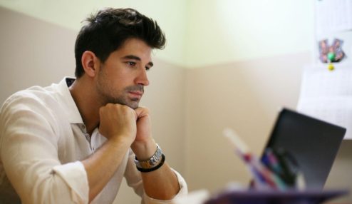 Profissional trabalhando em um notebook em um escritório, analisando informações com expressão concentrada. A imagem representa gestão, produtividade e tomada de decisões no ambiente corporativo.