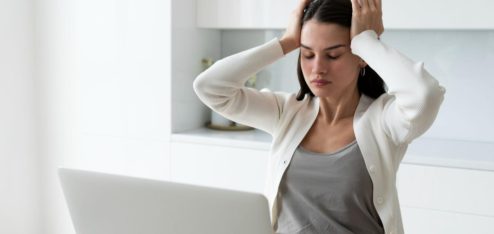Esta imagem retrata uma cena comum de estresse, cansaço ou sobrecarga mental no ambiente de trabalho.