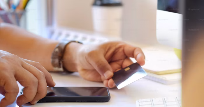 Pessoa segurando um cartão de credito: Foto: Unsplash