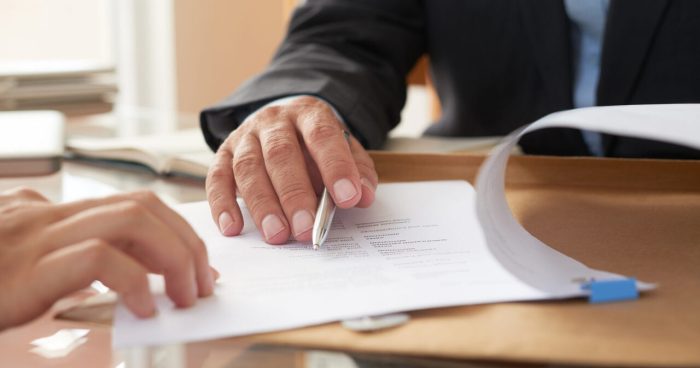 Pessoa mostrando um contrato de trabalho por prazo determinado para outra pessoa - Foto: Freepik