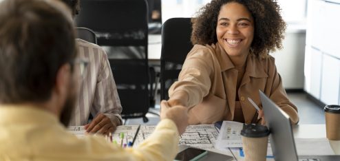 Pessoa recepcionando outra sentada em uma mesa em um escritório - Foto: Freepik