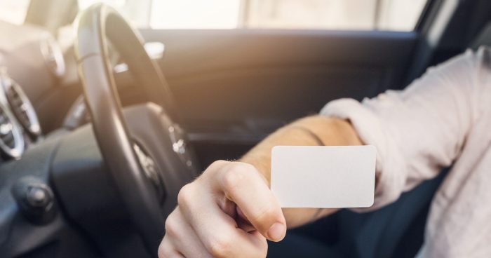 Pessoa dentro de um carro segurando um cartão